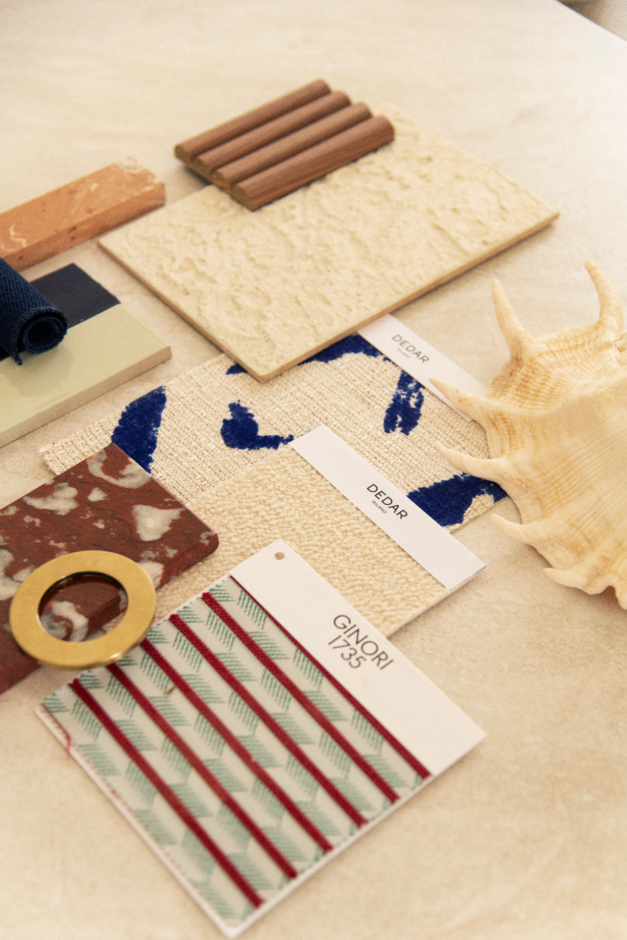 Curated material samples including marble, terracotta, woven leather, wood and patterned textiles